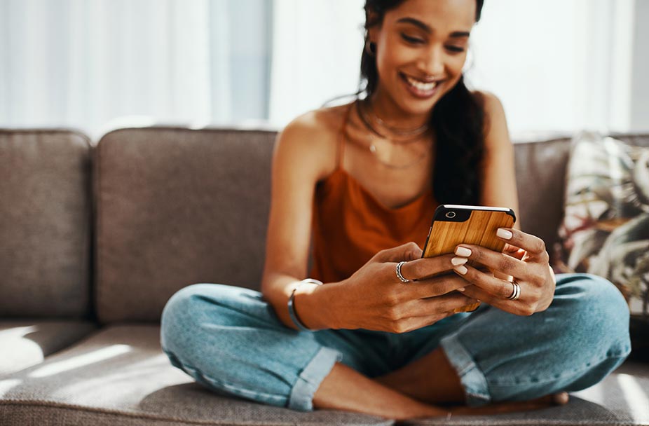 Woman sitting on couch and smiling at phone